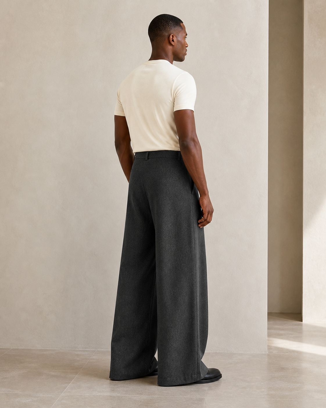 Modelo con pantalón gris oscuro de doble pinza, vista posterior tres cuartos