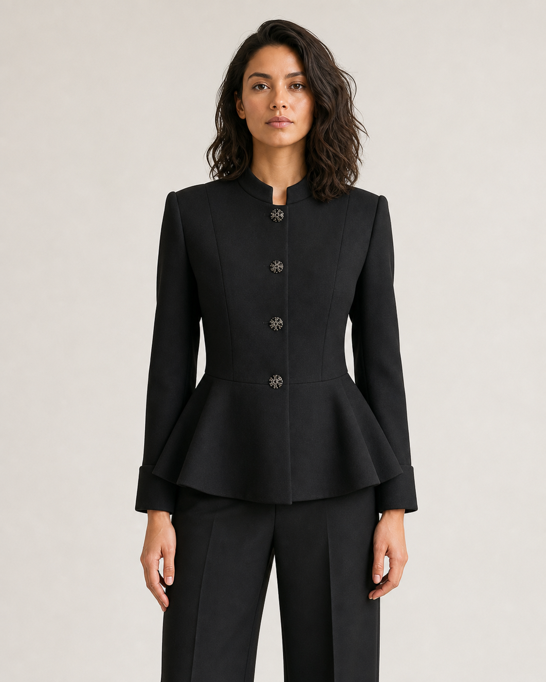 Detalle del cuello, los cuatro botones ornamentales y el peplum del blazer negro