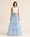 Mujer con falda larga azul claro, canesú estructurado de cinco botones y capas translúcidas, vista frontal