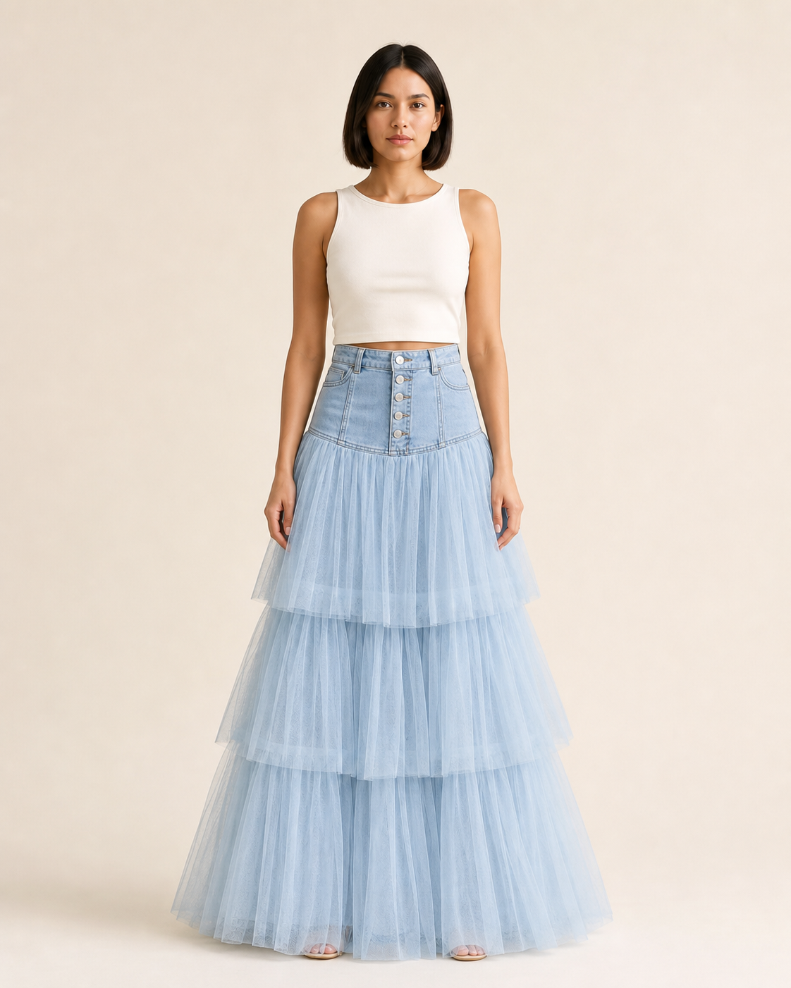 Mujer con falda larga azul claro, canesú estructurado de cinco botones y capas translúcidas, vista frontal