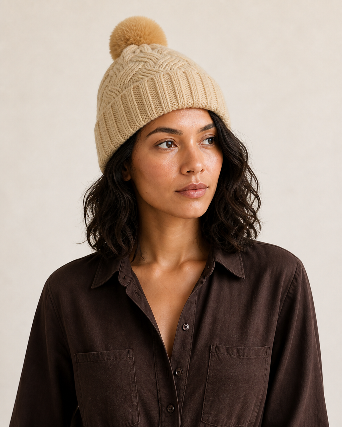 Detalle del borde acanalado, las trenzas y el pompón del gorro beige