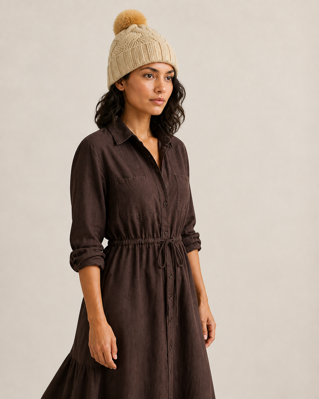 Perfil de mujer con gorro beige de punto trenzado y un pompón