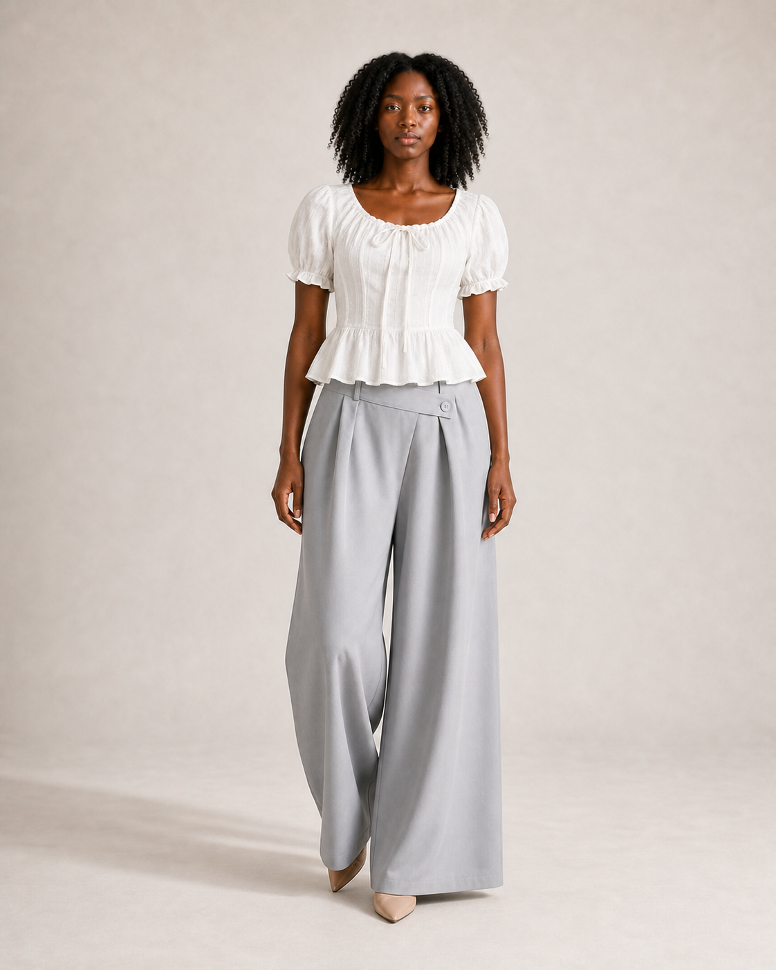 Mujer con top peplum blanco y pantalón gris, vista frontal en movimiento