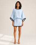 Mujer con conjunto azul claro de top de manga murciélago y minifalda, vista frontal de cuerpo entero